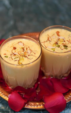 two glasses of creamy badam shake garnished with saffron strands