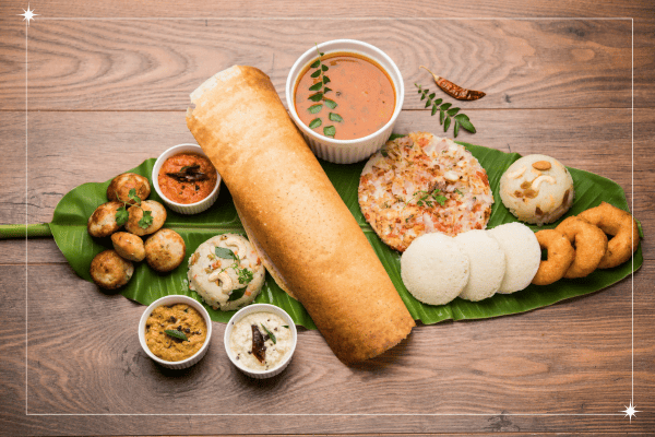 A leaf is full with dosa, idli and coconut chutney