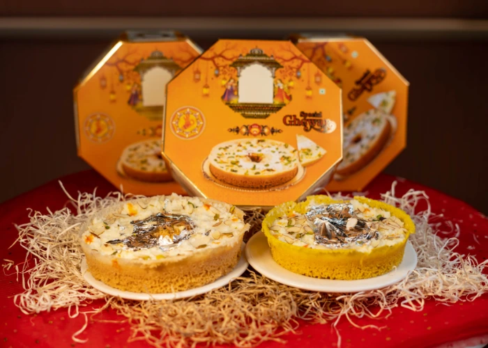 special ghughra festive sweet boxes with traditional indian sweets garnished with dry fruits and silver foil