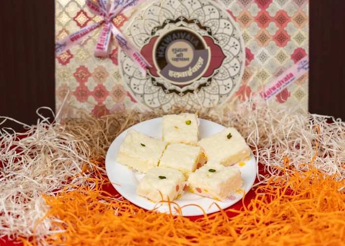 traditional indian sweets presented on a white plate, packaged in an elegant gift box by halwaivala