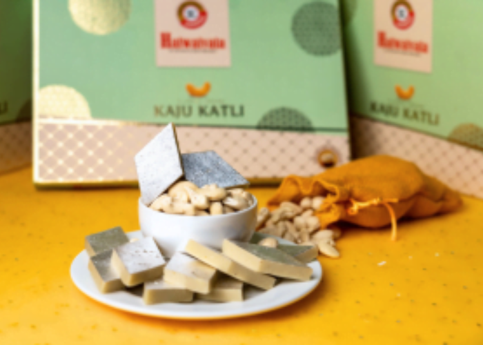 a traditional indian sweet covered in edible silver leaf, with additional pieces stacked in a small white bowl