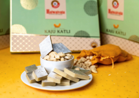 a traditional indian sweet covered in edible silver leaf, with additional pieces stacked in a small white bowl