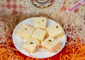 delicious indian milk barfi kalakand topped with pistachios, served on a white plate with decorative background