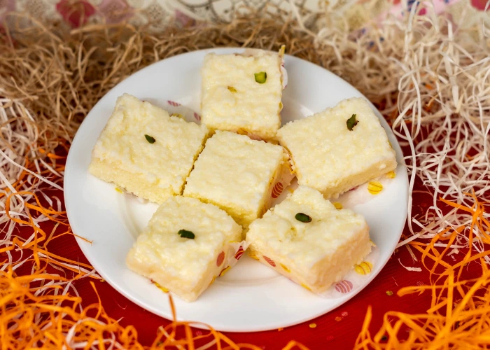 soft and creamy milk-based sweets garnished with pistachios, beautifully arranged on a white plate