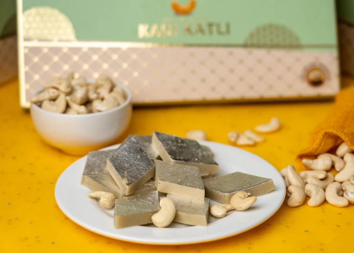 delicious kaju katli sweets garnished with silver leaf, served on a white plate with cashews